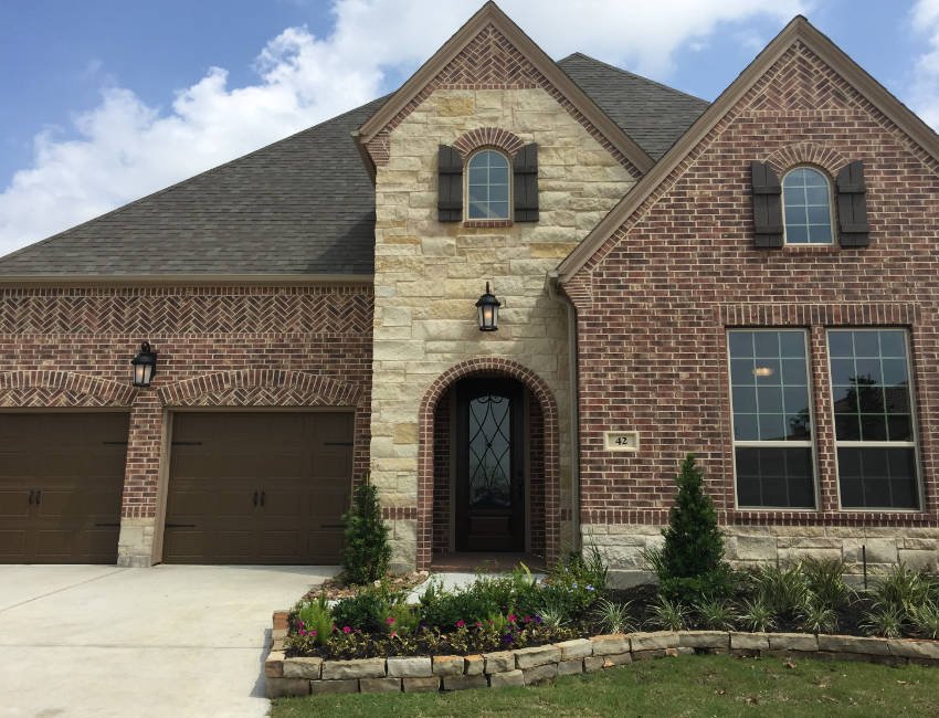 Texas brick and limestone home with arched entry and landscaped front yard